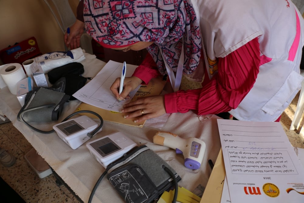 PMRS volunteer Duaa writes in a medical report in mobile clinic in the village of Al Uqban