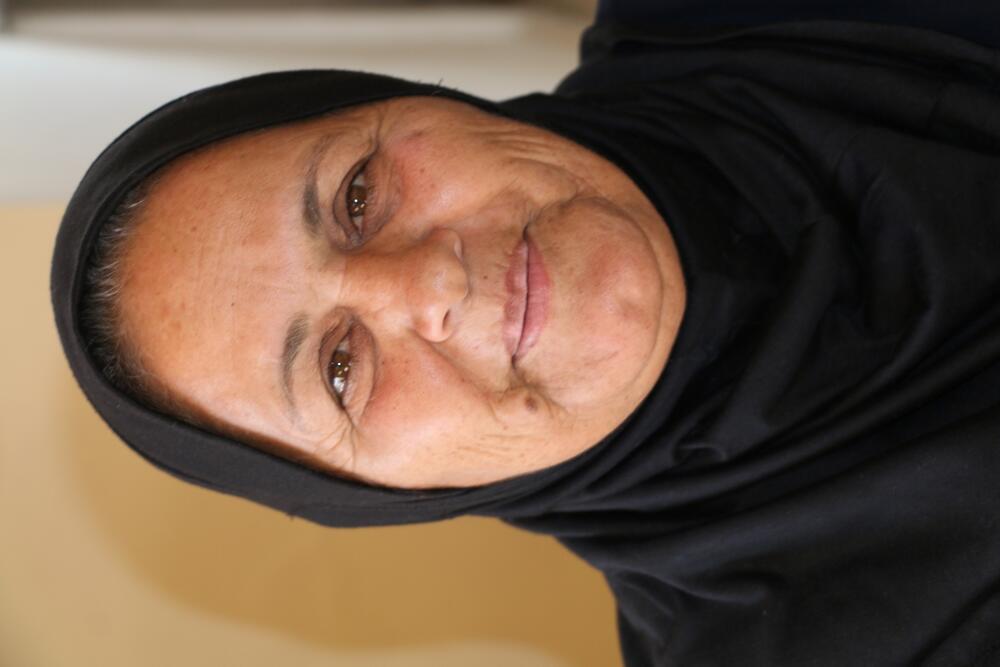 Mariam, 55, from Al Uqban Village, smiles at the camera.