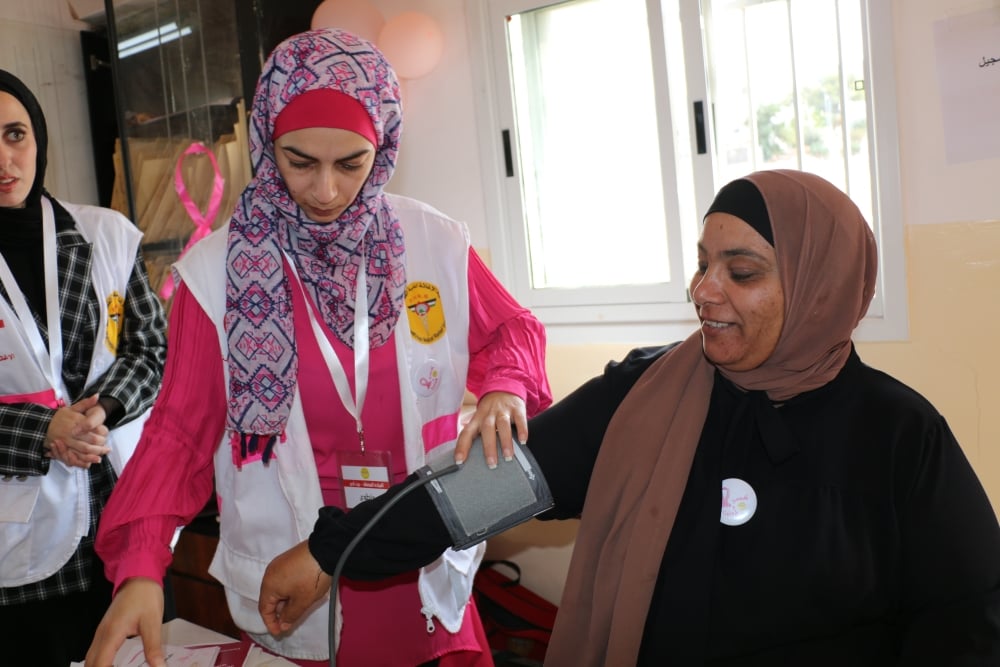 Duaa, a volunteer with Palestinian Medical Relief Society, takes the blood pressure of patient.