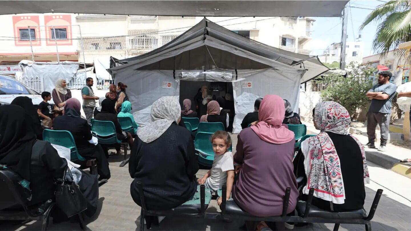 In Gaza, women and girls are sitting on benches, waiting at a UNFPA-supported mobile clinic waiting for services
